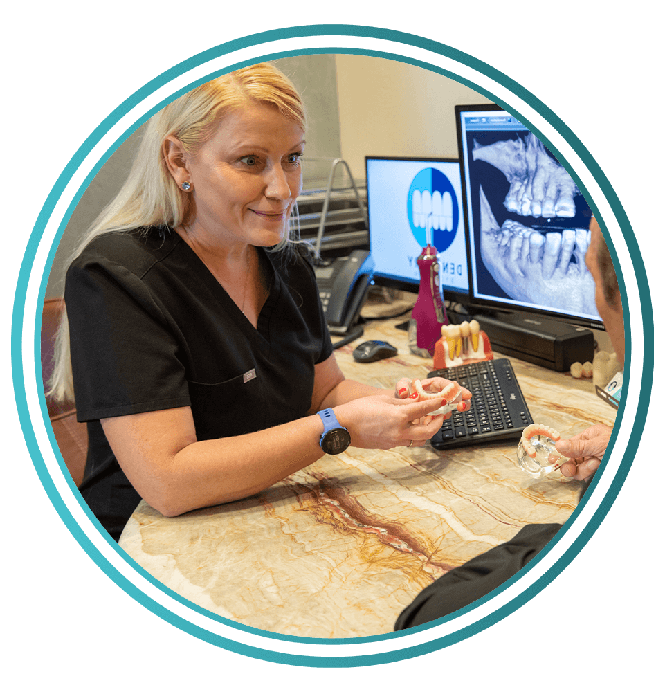 frame of staff member showing off dental implant model within the consultation office