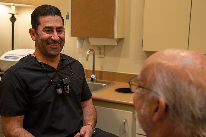 doctor smiling brightly while going over dental procedure information with patient